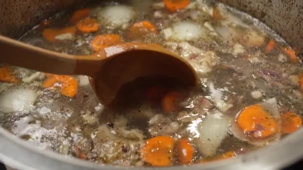用一个大木勺搅拌用胡萝卜和香料做的骨肉汤 — 图库视频影像