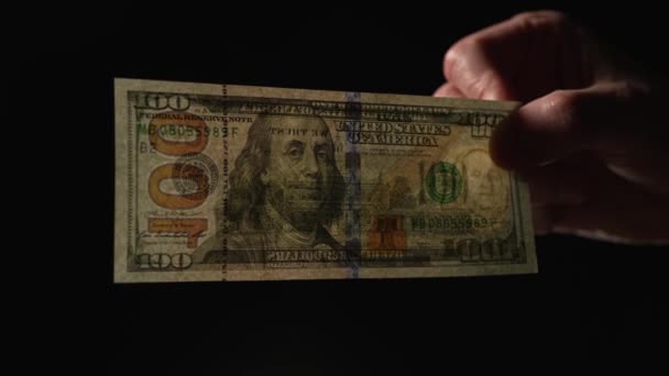 100ドル紙幣は 黒い背景の光を通して示しています — ストック動画