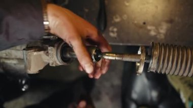 Tamirci bir araba tamirhanesinde bakım direksiyon rafı taşır.