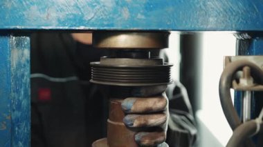 Bir zanaatkar, sanayi basınından bir parça alıp yakın çekime bakıyor.