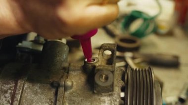 Teknisyen klima kompresörünü yağ tenekesiyle dolduruyor.