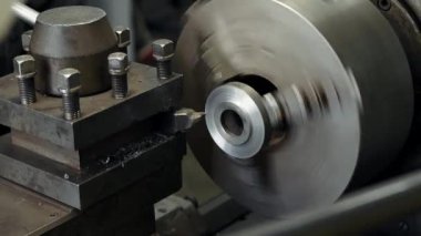 Torna tezgahındaki metal parçasının yakın çekim işlemleri, torna işlemleri metal parçasının kenarı ve metal parçacıklar farklı yönlere dağılmış.