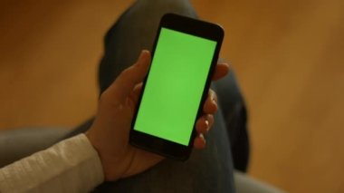 Kullanıcı yeşil ekranlı akıllı telefonu tutuyor ve sola kaydırıyor. Yüksek kaliteli FullHD görüntüler