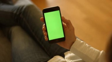 Kullanıcı yeşil ekranlı akıllı telefonu tutuyor ve sola kaydırıyor. Yüksek kaliteli FullHD görüntüler