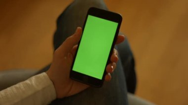 Kullanıcı elinde yeşil ekran ve kaydırmalı bir akıllı telefon tutuyor. Yüksek kaliteli FullHD görüntüler