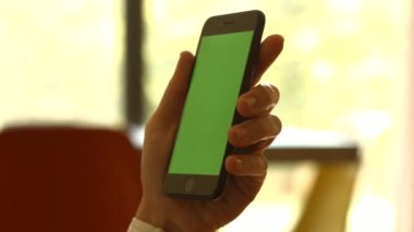 Kullanıcı elinde yeşil ekranlı akıllı telefon tutuyor. Yüksek kaliteli FullHD görüntüler