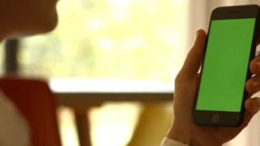 Kullanıcı elinde yeşil ekranlı akıllı telefon tutuyor. Yüksek kaliteli FullHD görüntüler