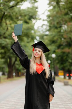 Mezun bir kız diplomasını elinde tutuyor. Yüksek kalite fotoğraf