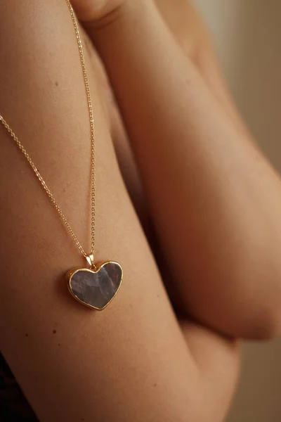Gold heart-shaped amulet on a girls shoulder. High quality photo