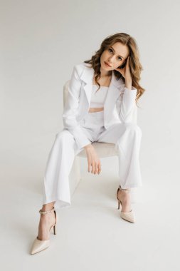 Pretty girl in a white trouser suit against a white background. High quality photo