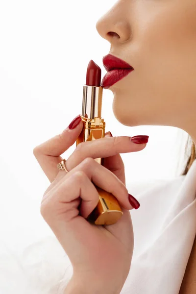 A girl apply her lips with red lipstick on a white background. High quality photo