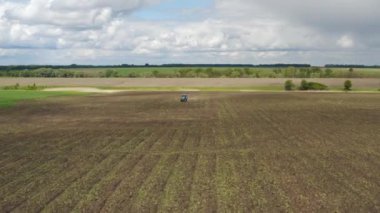 Tarlada çalışan traktörlü bir çiftçinin hava görüntüsü, kabuk kaldırma, toprak havası ve genç otları kaldırma. Ekinleri yeniden ekmeden önce toprak hazırlığı
