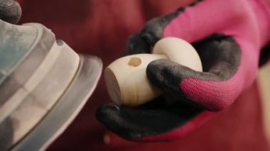 Eldivenli bir el zımparalama sırasında tahta bir parça tutuyor. Tahtayı zımparalama makinesi ile zımparalama işlemi görülebilir, pürüzsüz bir yüzey sağlar