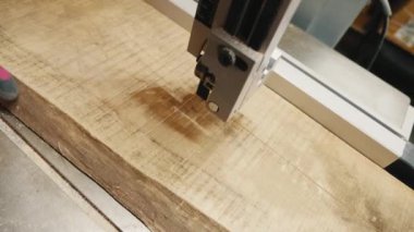 Tahta bir tahtanın işlendiği bir marangozluk makinesinin çalışma süreci. Tahtayı kesen testere, infazda kesikler ve hassasiyet gösteriyor.
