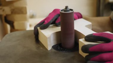 Eldivenli bir el zımpara makinesinde boş bir tahta ile çalışır. Zımparalama işlemi, kumlama silindirinin yüzeyi pürüzsüz hale getirerek döndüğü yerde görülebilir.