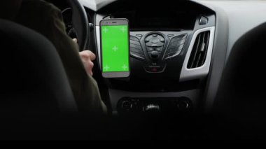 Bir adamın yakın plan görüntüsü. Dikey yeşil ekranda, bir cep telefonunun gösterge panelinde kayıyor.