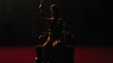 Themis 'in elinde pullar ve gözleri bağlı bir heykeli karanlık arka plandaki loş ışıkla aydınlatılır.