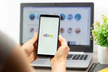 Kyiv, Ukrayna - 15 Ekim 2022: eBay 'de elinde bir akıllı telefonun ekranında online mağazaları kullanarak faturaları ödemek ve mal satın almak için. E-ticaret.