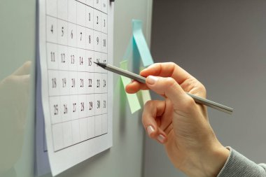 Kadının eli takvimdeki tarihi işaretliyor. Planlama ya da teslim tarihi kavramı.