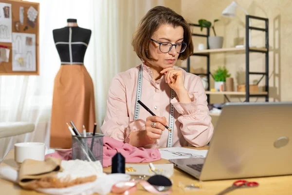 stock image Woman fashion designer working on sketches of clothes at the table.