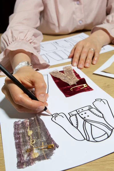 Woman fashion designer draws sketches of clothes on paper.