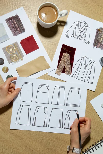 Woman fashion designer draws sketches of clothes on paper.