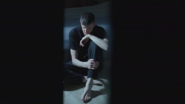 Yalnız, üzgün bir adam karanlık bir odada oturuyor. Akıl sağlığı kavramı. Depresyon.