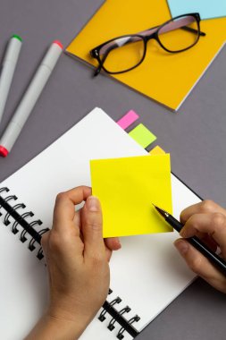 İş planlama konsepti. Masaüstüne not yazmak için bir kalem ve boş bir çıkartma ile el..