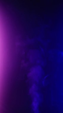 Dikey video. Kıvırcık duman renkli bir arka planda hareket eder. Soyut duman çizgileri. Neon arkaplanda dumanın canlandırması