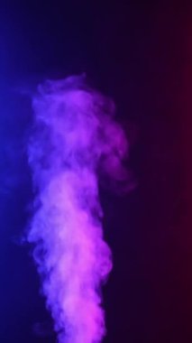 Dikey video. Kıvırcık duman renkli bir arka planda hareket eder. Soyut duman çizgileri. Neon arkaplanda dumanın canlandırması