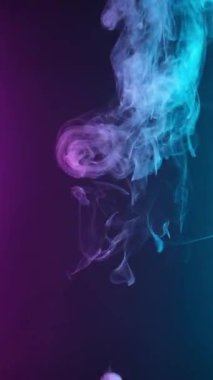Dikey video. Kıvırcık duman renkli bir arka planda hareket eder. Soyut duman çizgileri. Neon arkaplanda dumanın canlandırması