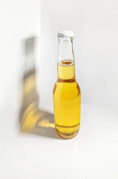 Bottle of beer. Light beer bottle isolated with shadow and light yellow reflections on a white background.