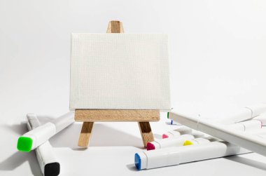 Beyaz brandalı küçük ahşap sehpa ve beyaz arka planda keçeli kalemler. Yaratıcılık, hobi, beyaz tuval.