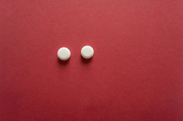white pill with medical pills isolated on red background. minimal medicine concept with copy space.