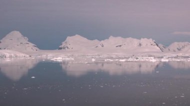 Antarktika. Buzdağları. Küresel ısınma ve iklim değişikliği. Güzel doğa. Karlı dağların ve buzlu kıyıların manzarası. Ayna yansıması açık okyanusta yüzen güzel mavi buzdağı. Buzullar