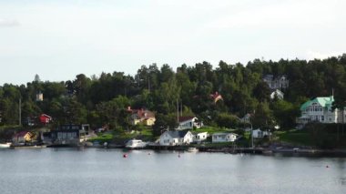 Resimli bir fiyordun kıyısındaki kır evleri. Güzel doğa. Fiyort kıyısında kırmızı kulübeleri olan pitoresk bir köy. Atlantik Okyanusu kıyısında parlak kırmızı evler.