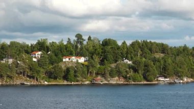 Resimli bir fiyordun kıyısındaki kır evleri. Güzel doğa. Fiyort kıyısında kırmızı kulübeleri olan pitoresk bir köy. Atlantik Okyanusu kıyısında parlak kırmızı evler.
