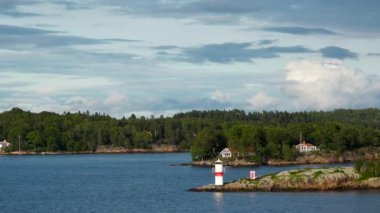Resimli bir fiyordun kıyısındaki kır evleri. Güzel doğa. Fiyort kıyısında kırmızı kulübeleri olan pitoresk bir köy. Atlantik Okyanusu kıyısında parlak kırmızı evler.