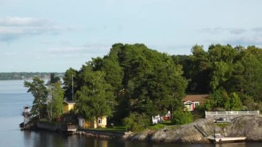 Stockholm Takımadaları. İsveç takımadaları yazın güneşli bir günde. Sahildeki yeşil orman ağaçları. İsveç doğası. Stockholm takımadalarındaki adadaki orman, Baltık Denizi