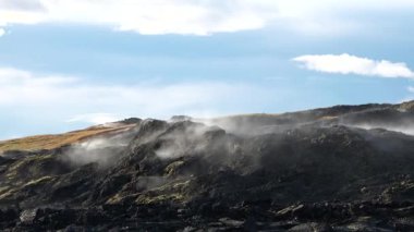 İzlanda. Dumanlı dağların ve dramatik gökyüzünün olduğu güzel bir doğal manzara. Fümeroller