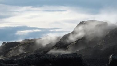 İzlanda. Dumanlı dağların ve dramatik gökyüzünün olduğu güzel bir doğal manzara. Fümeroller