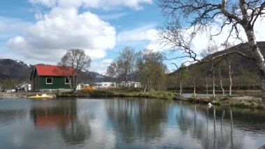 Kırmızı evleri olan küçük bir balıkçı köyünün manzarası. Beyaz karla kaplı güzel dağlar. Lofoten Adası, Norveç. Fiyort kıyısındaki kır evi. Geleneksel ahşap balıkçıların evleri..