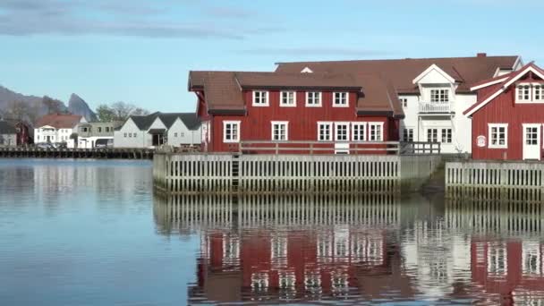 赤い家を有する小さな漁村の風景 美しい山々が白い雪を覆いました ノルウェーのロフォテン島 フィヨルドの岸にコテージがある 伝統的な木製の古い漁師の家 — ストック動画
