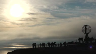 Renkli Bulutlar ve Globe Anıtı 'nın Silueti ve insanlarla Sunset' te Nordkapp. Gece yarısı Kuzey Burnu 'nda, Mageroya, Norveç' teki dünya anıtı.