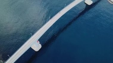 Norveç 'e git. Reine, Lofoton Adaları 'ndaki köprünün insansız hava aracı görüntüleri. Norveç fiyorduna giden yol manzarası, Lofoten adası dağları, kulübeleri olan geleneksel balıkçı köyü. Güzel Norveç manzarası