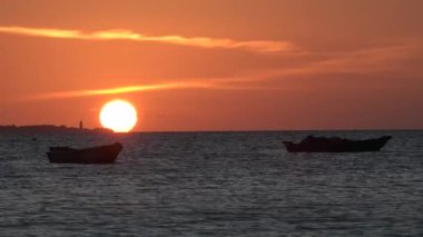 Denizde Gün Batımı Güneşi. Kumsalda Turuncu Kırmızı Gün Doğumu. Horizon 'da Tekne Siluetleriyle Denizde Gün Batımı. Sakin Deniz 'de Güzel Gün Doğumu. Tatilde Sabah Tatil Köyü. Güneş ışınları okyanus suyuna yansıyor