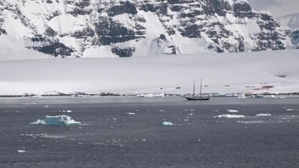 氷の海岸の間の凍った冬の水の風景に浮かぶボート 氷山に囲まれた海での遠足ボート 南極海でのボート 南極半島を探索する — ストック動画