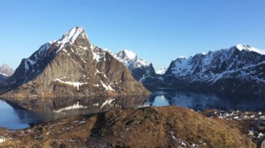 Norveç. Lofoten Adaları. Hava görüntüsü. Deniz suyuna yansıyan beyaz karla kaplı dağlık kayalık tepelerin nefes kesici kuş bakışı görüntüsü. Kışın Lofoten 'in nefes kesici panoramik fiyortları.