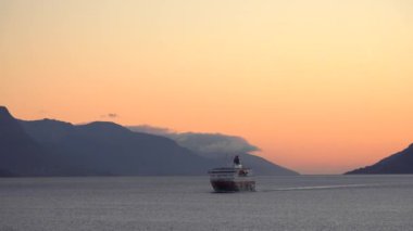 Etkileyici yolculuklar. Norveçli Fjord Sunset Cruise. Karlı dağda sinematik pembe gün batımı. Norveç kutup denizinin karla kaplı fiyortlarla çevrili manzarası. Seyahat kavramı.