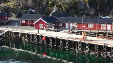 Sudaki yansıma. Karlı dağlar, balıkçı köyü. Okyanustaki parlak kırmızı evler. Norveç 'teki Lofoten adaları. Tipik kırmızı kulübeleriyle popüler bir turizm merkezi. Norveç rorbu 'su.
